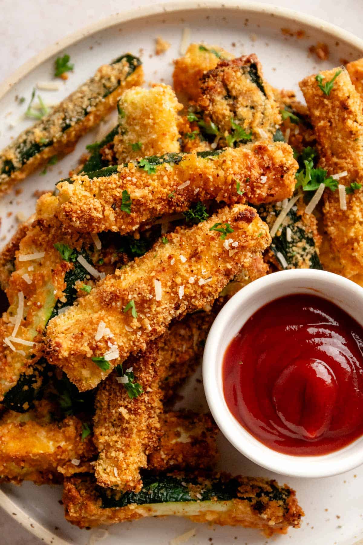 perfectly roasted golden brown zucchini fries served with red sauce.