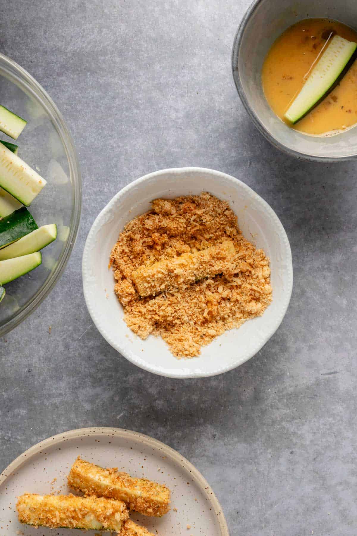 coating zucchini stick in almond flour breading.