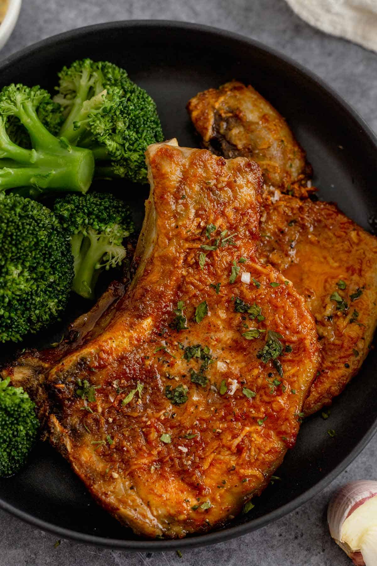 cooked bone in pork chops in a bowl with broccoli