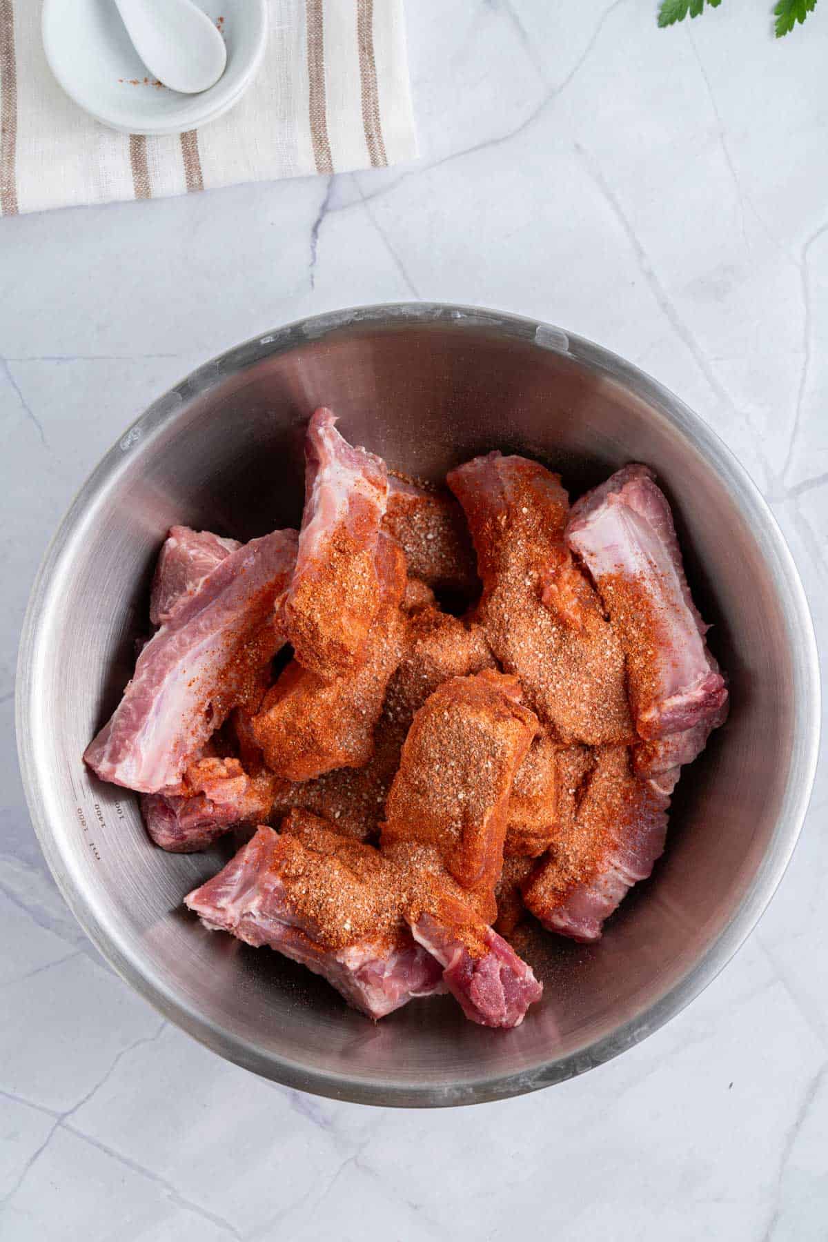 ribs in air fryer basket with seasonings.