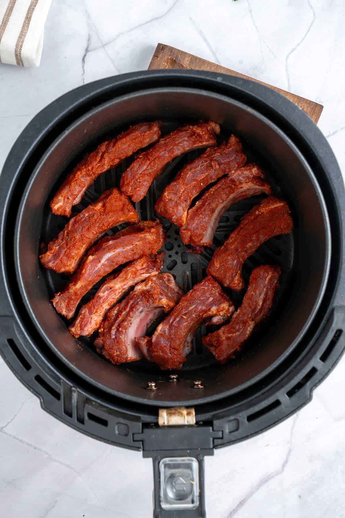 seasoned ribs in air fryer basket.