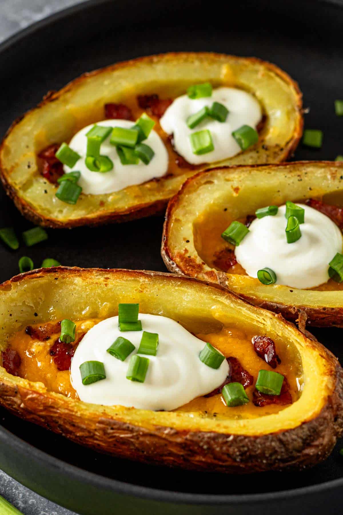 three potato skins with cheese, bacon and sour cream topping.