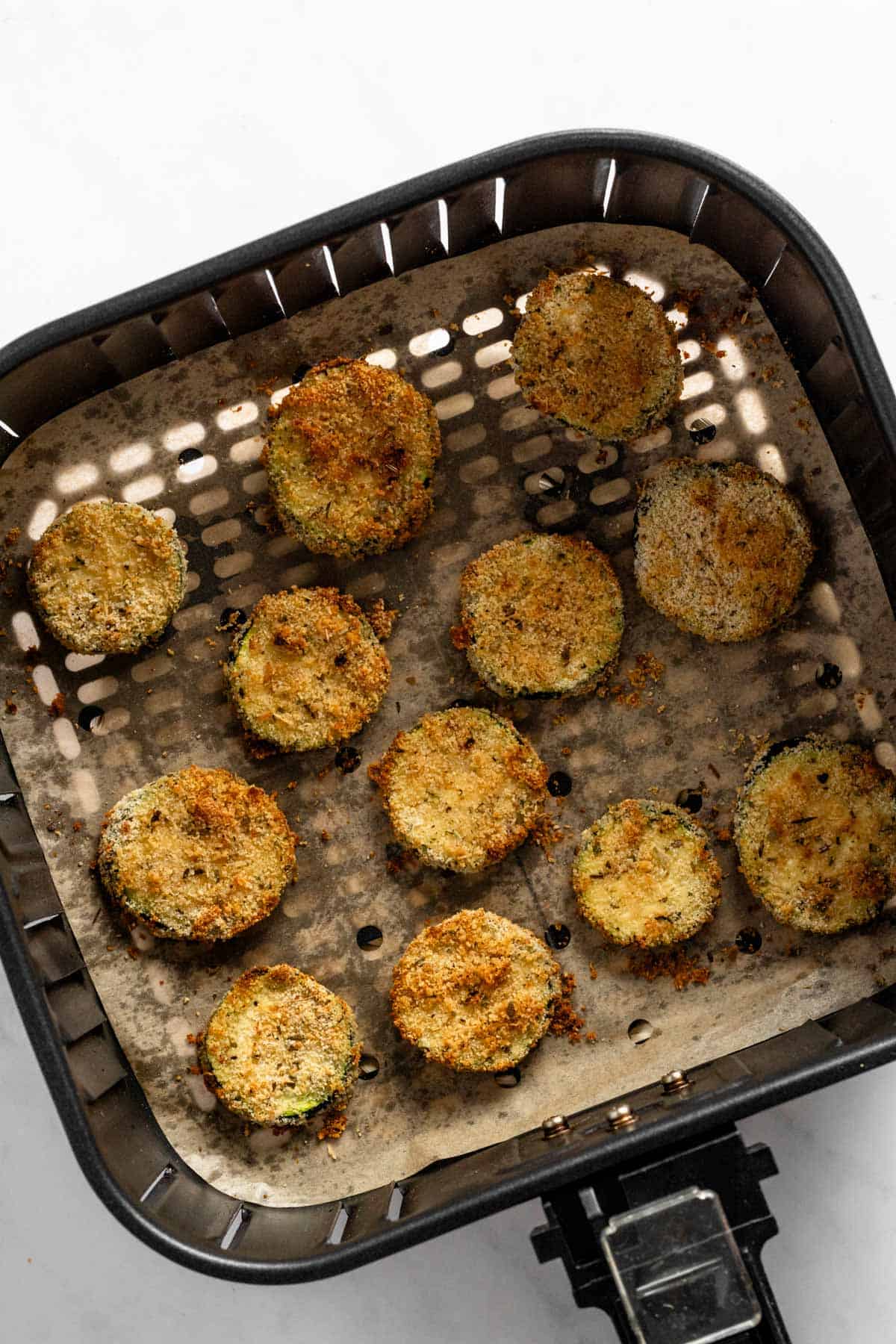 zucchini slices in air fryer basket right after cooking.