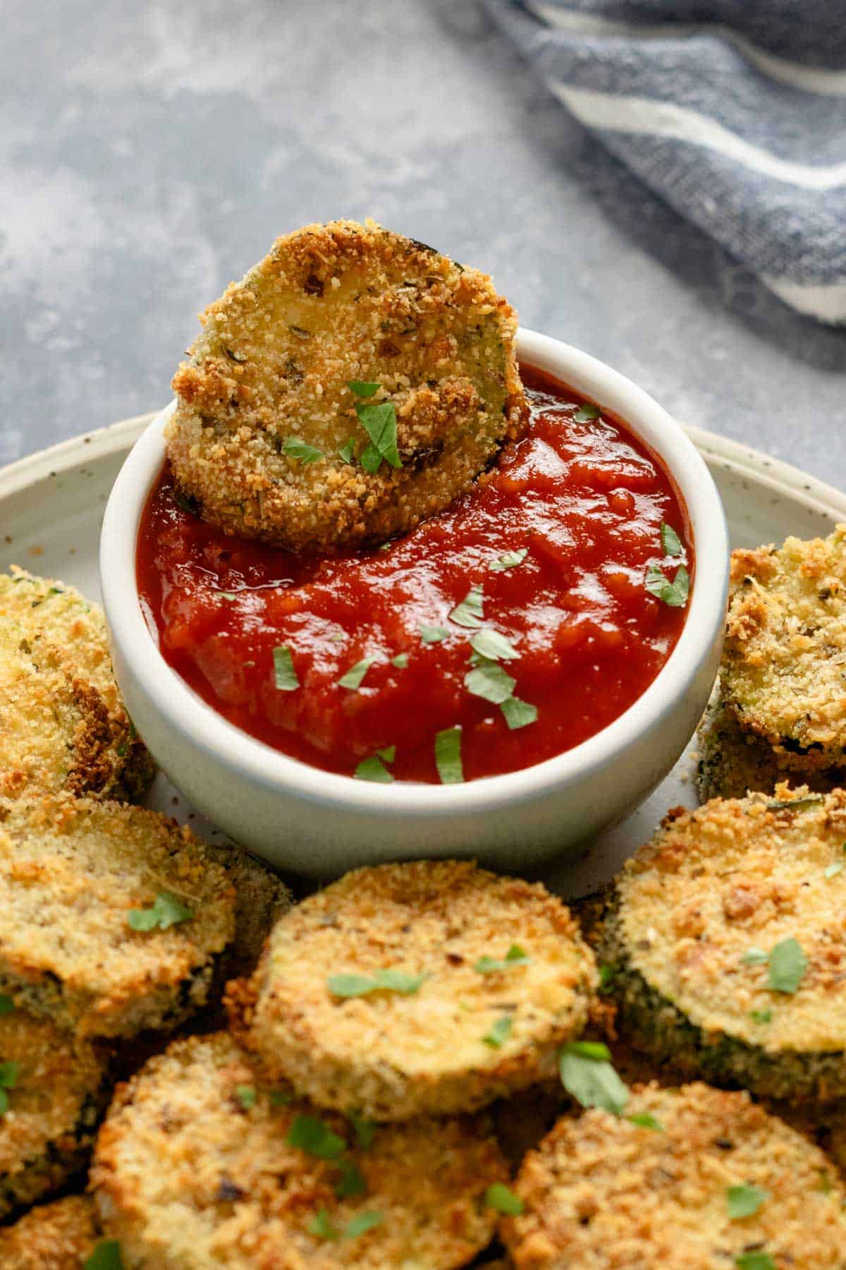 zucchini slice dipped into red sauce bowl.