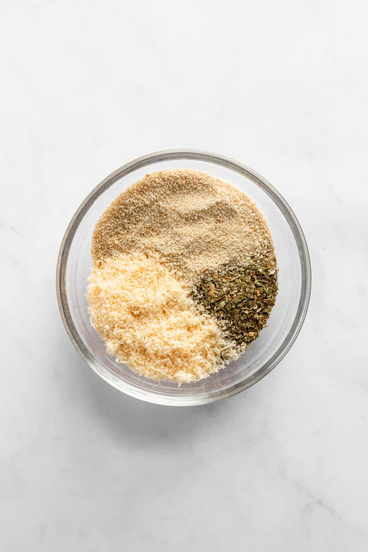 grated parmesan, breadcrumbs, salt, black pepper and italian herbs in a glass bowl.