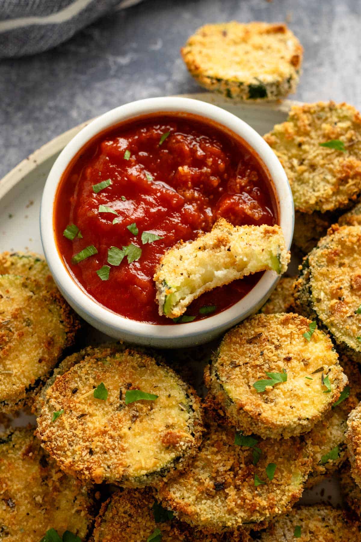 zucchini slice dipped into red sauce bowl.