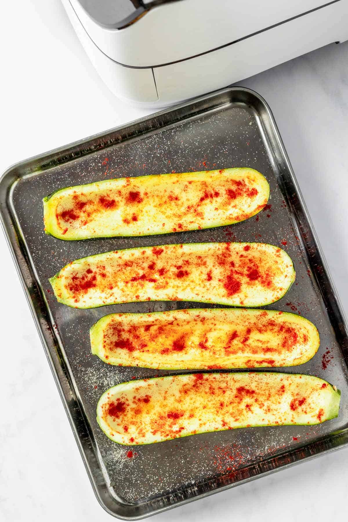 zucchini halves on a baking sheet with seasonings