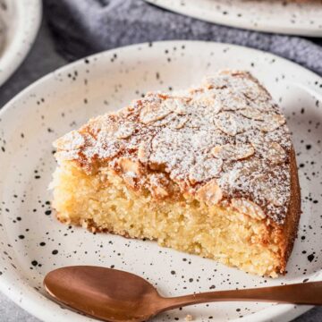 a slice of almond flour cake with flaked almonds and icing sugar on top