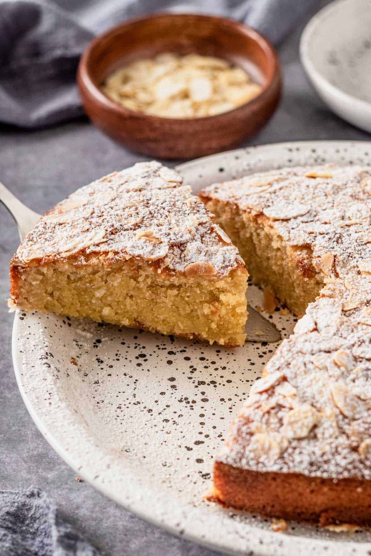 a slice of almond flour cake with flaked almonds and icing sugar on top