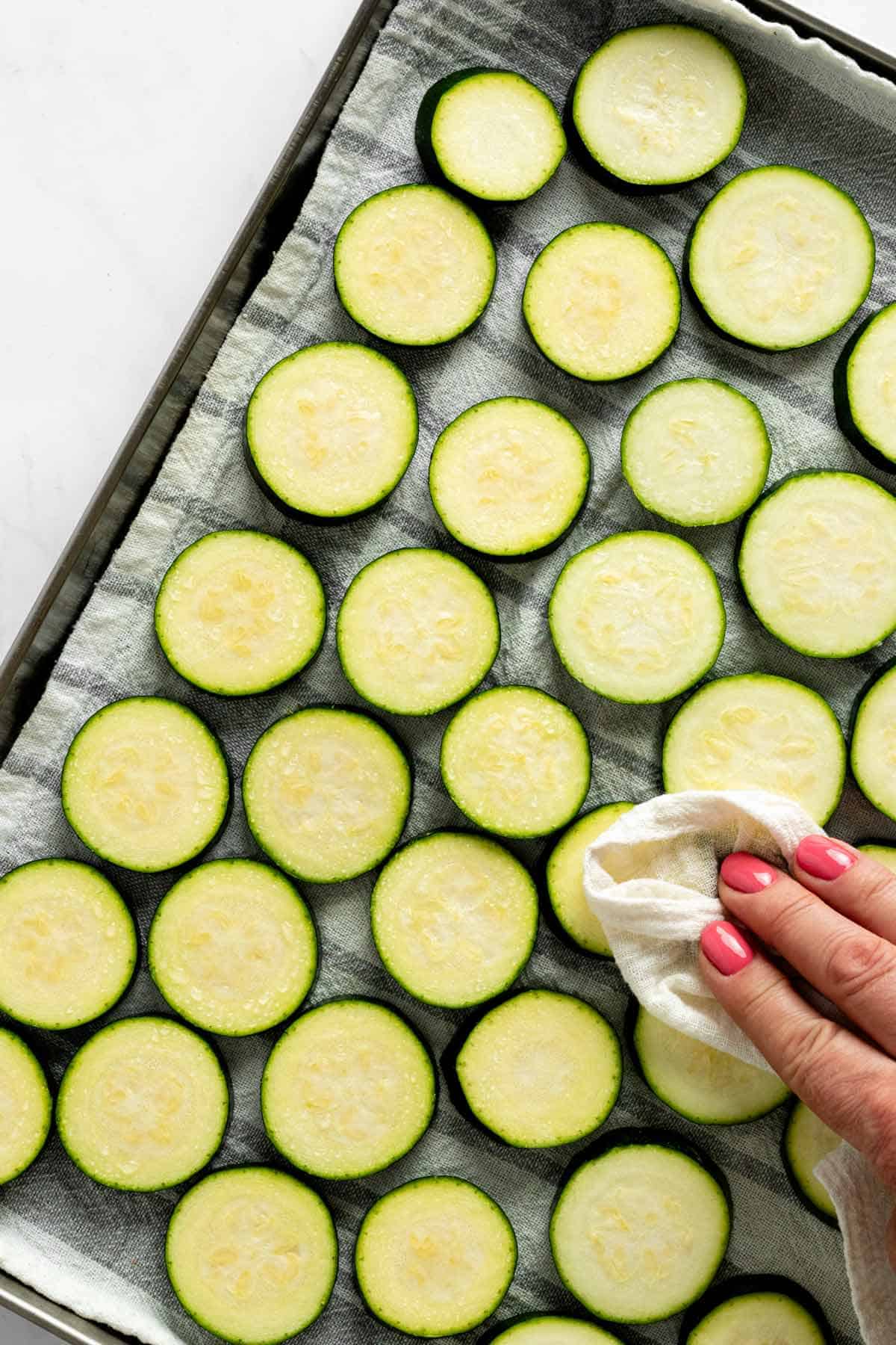 wiping excess water and salt from zucchini slices.