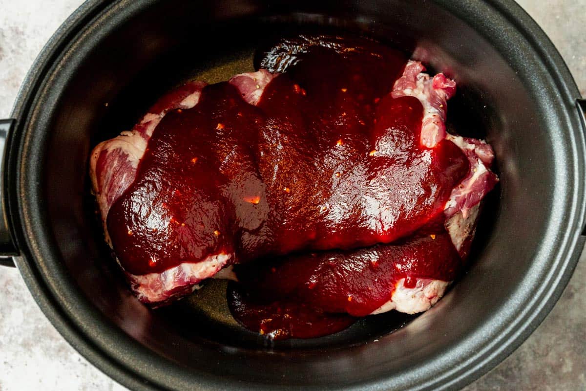 pork rib cage in a slow cooker with barbecue sauce