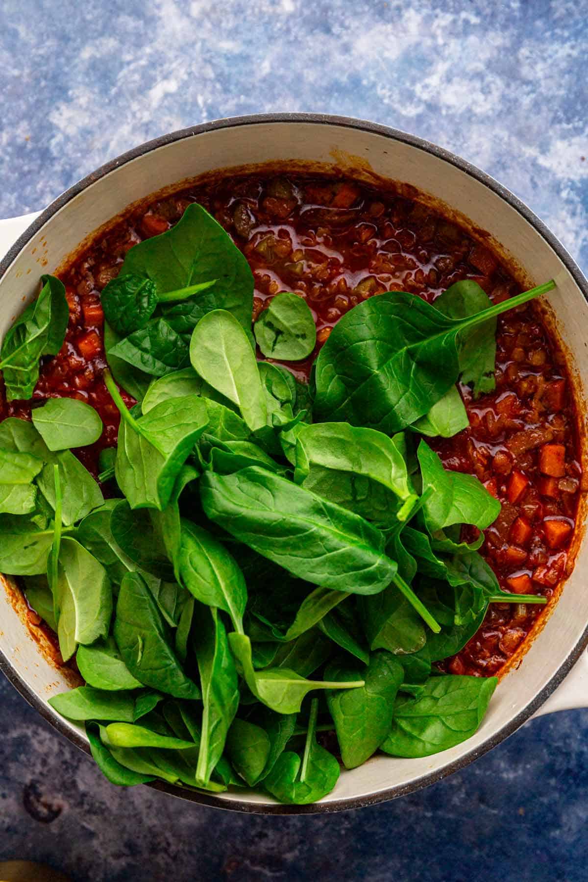 adding spinach to the pot.