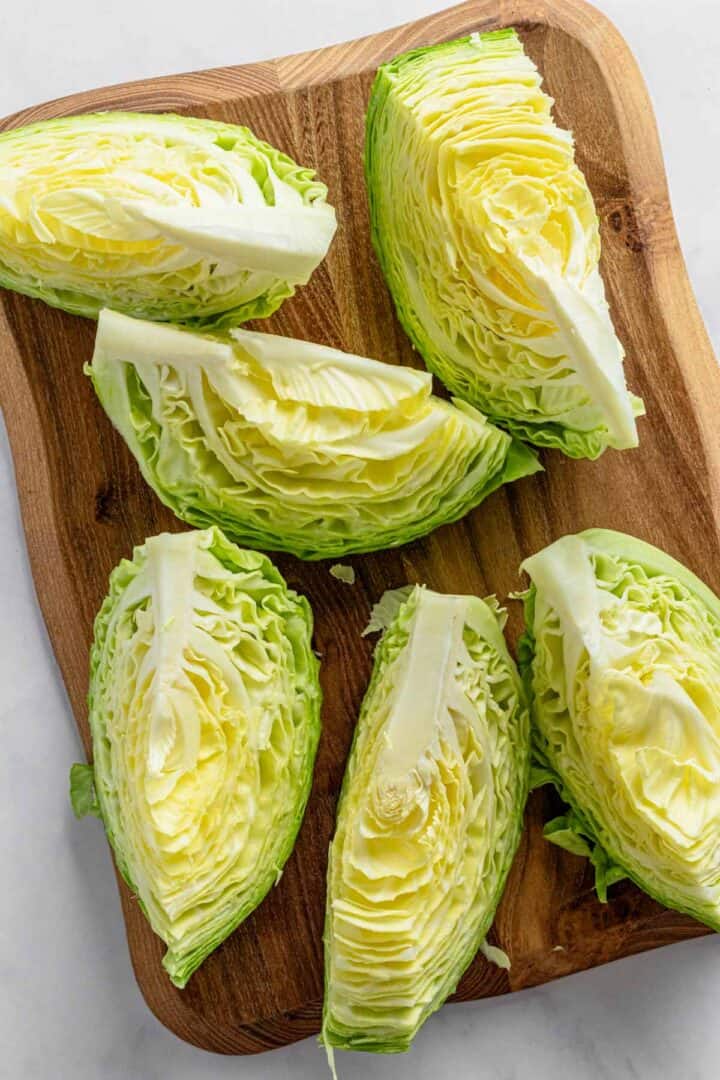 cabbage wedges on wooden cutting board.