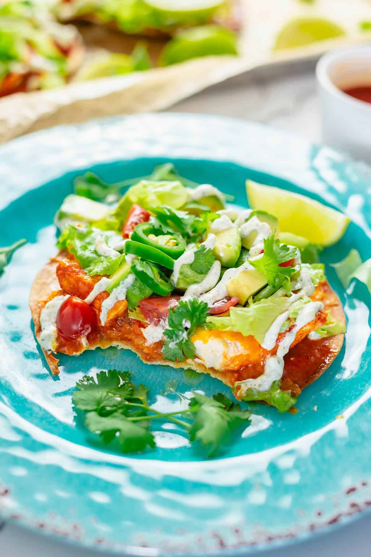 crispy tostadas with buffalo chicken toppings and ranch dressing close up shot on a blue plate