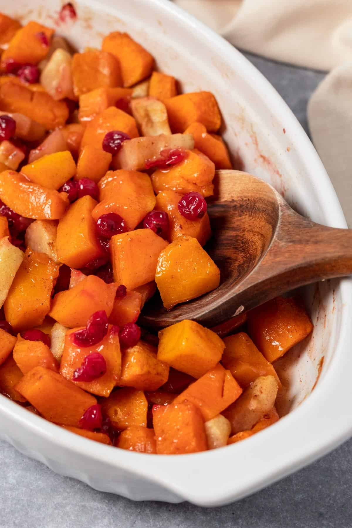 squash casserole in oval baking dish with apples and cranberries