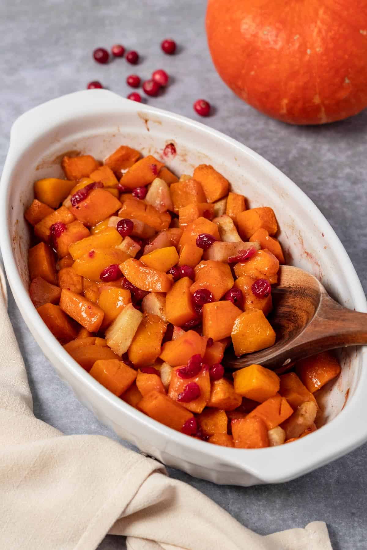 squash casserole in oval baking dish with apples and cranberries