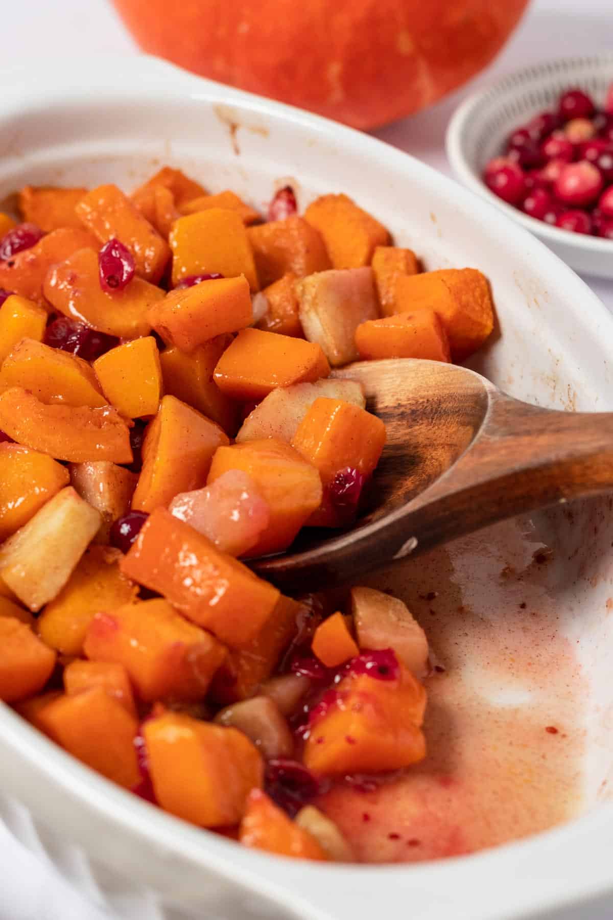 squash casserole in oval baking dish with apples and cranberries