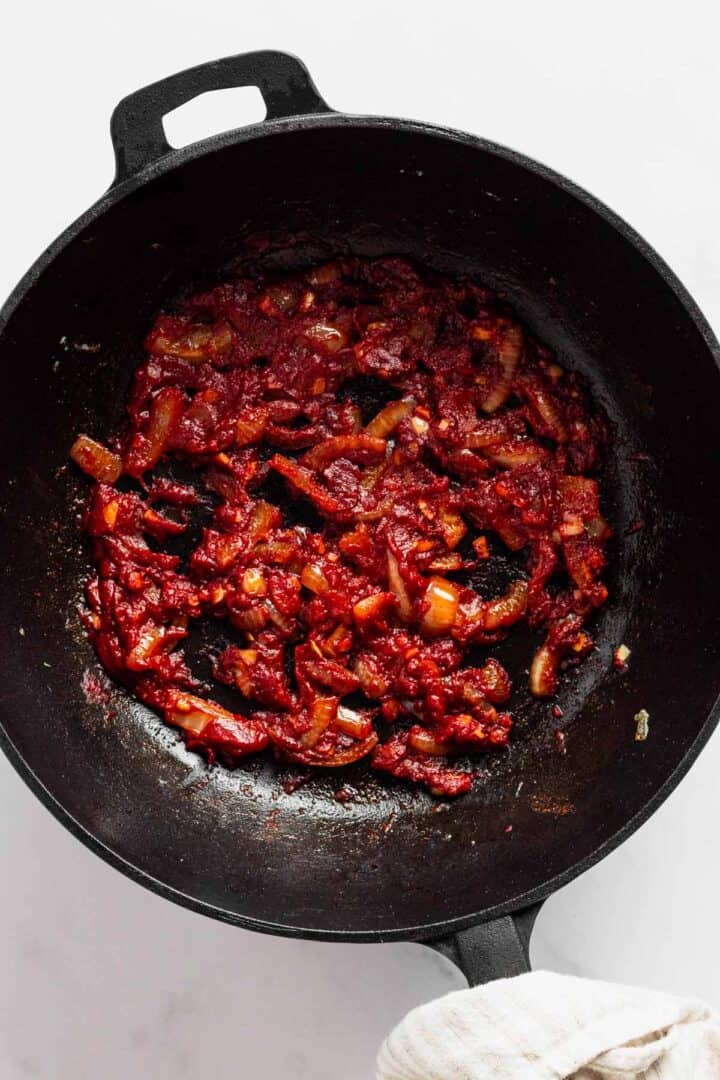 adding tomato paste to skillet.