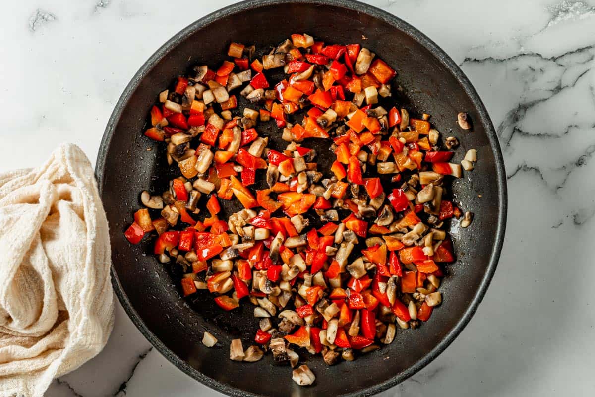 picture of bell peppers and onion cooking in a black skillet