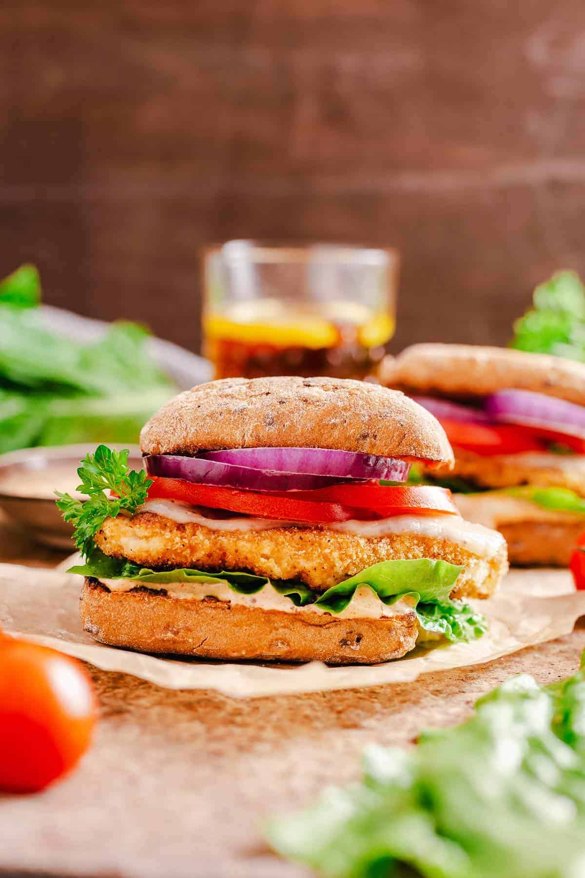 ciabatta chicken sandwich final image with a dark brown background and iced tea