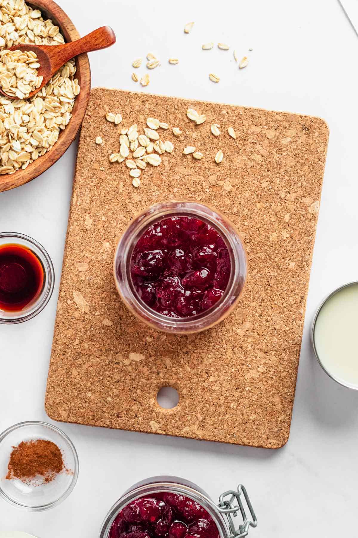 adding cranberry sauce to the jar with overnight oats.