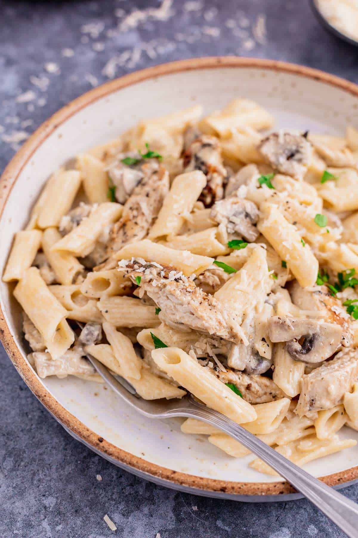 creamy garlic chicken and mushroom pasta in a white plate