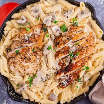 creamy garlic chicken and mushroom pasta in a black skillet