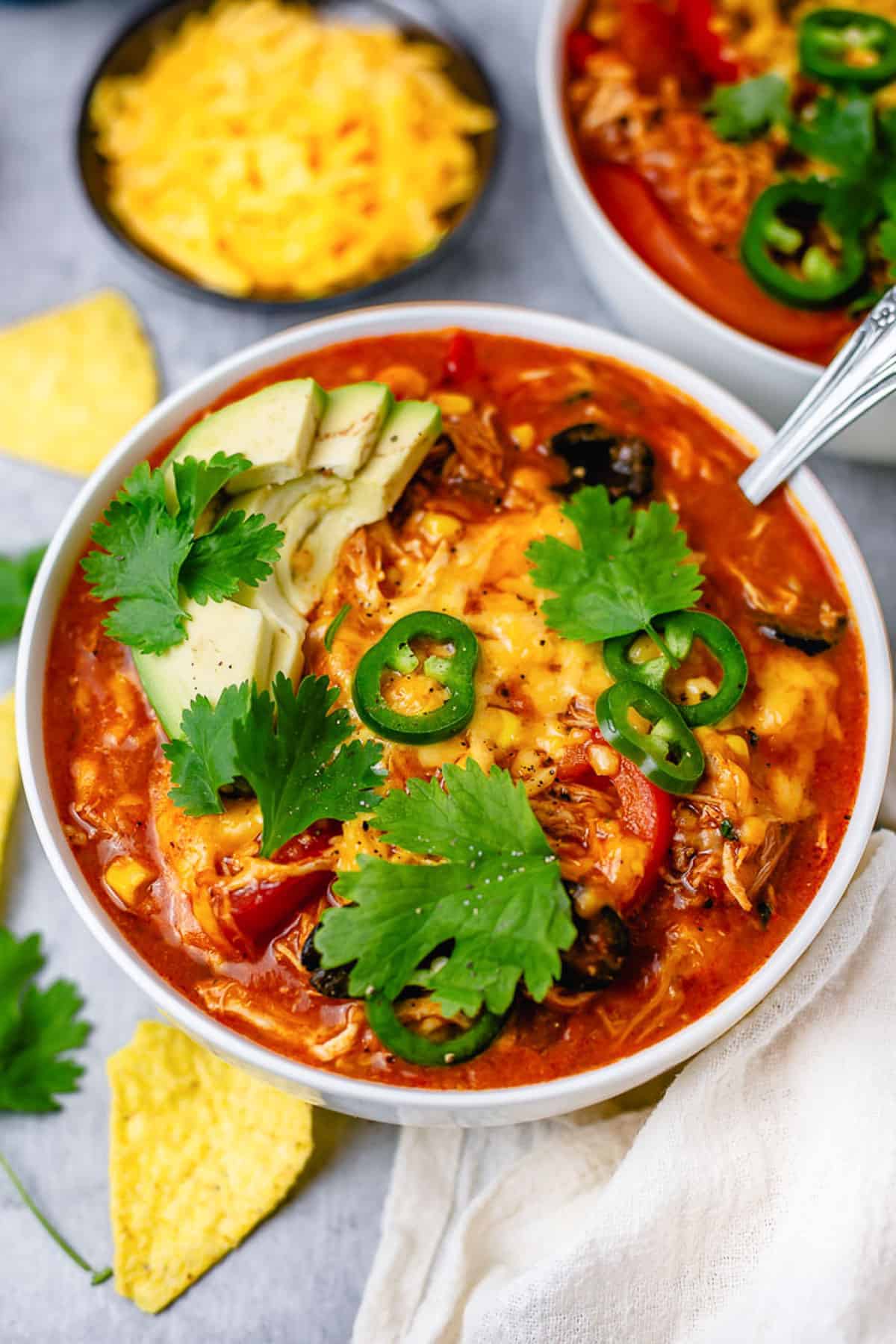 chicken enchilada in a bowl with avocado jalapeno tortilla chips on a gray background