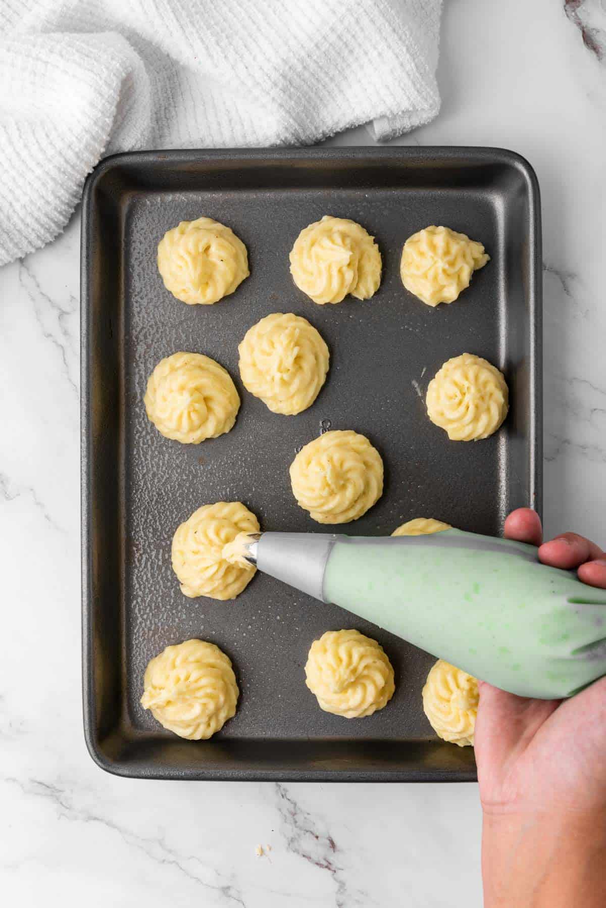 duchess potatoes piped onto baking sheet