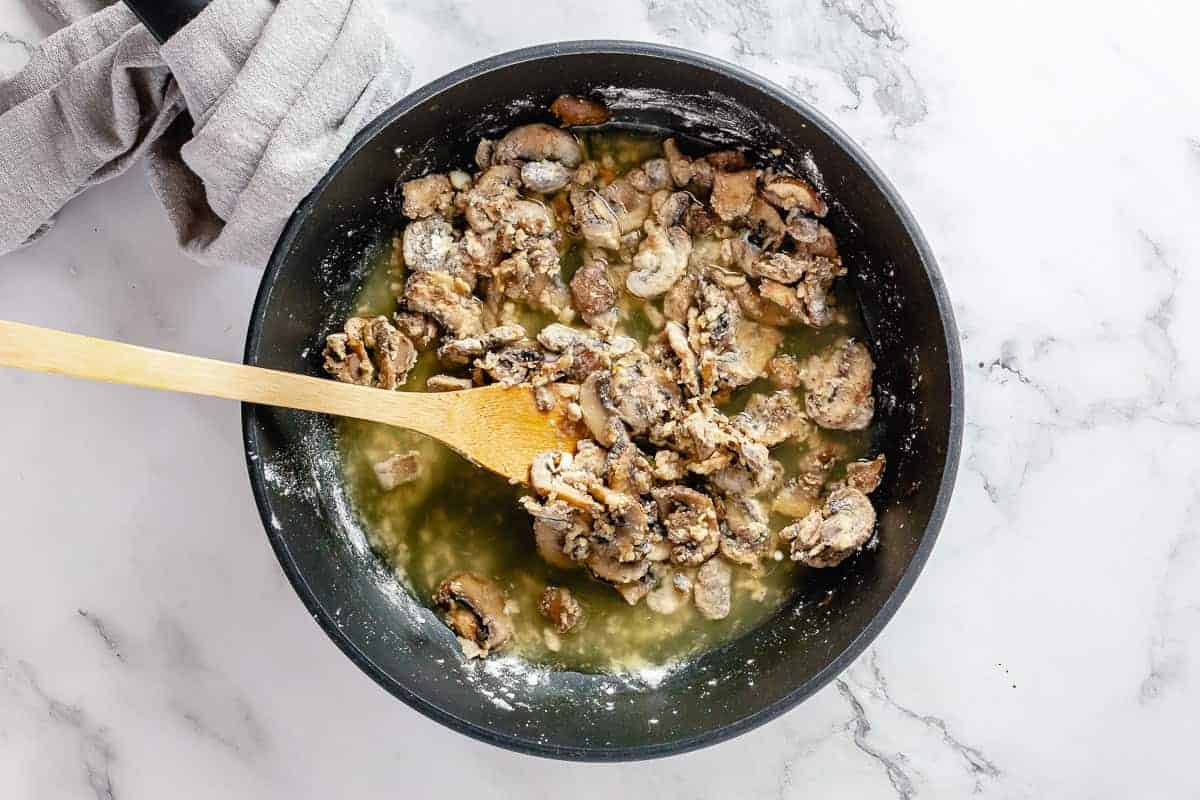 Flour stirred in mushrooms and garlic mixture in a skillet