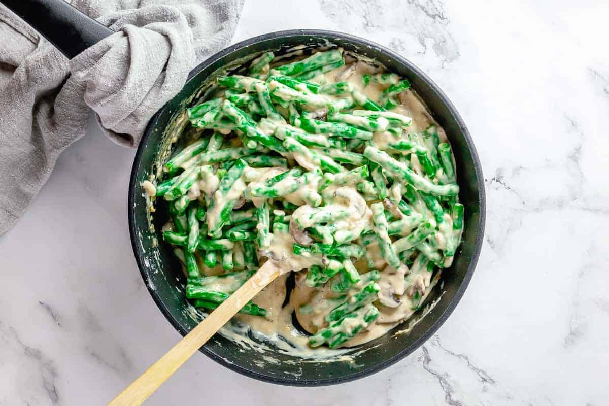 Freshly blanched green beans added to the skillet with creamy mushroom sauce.