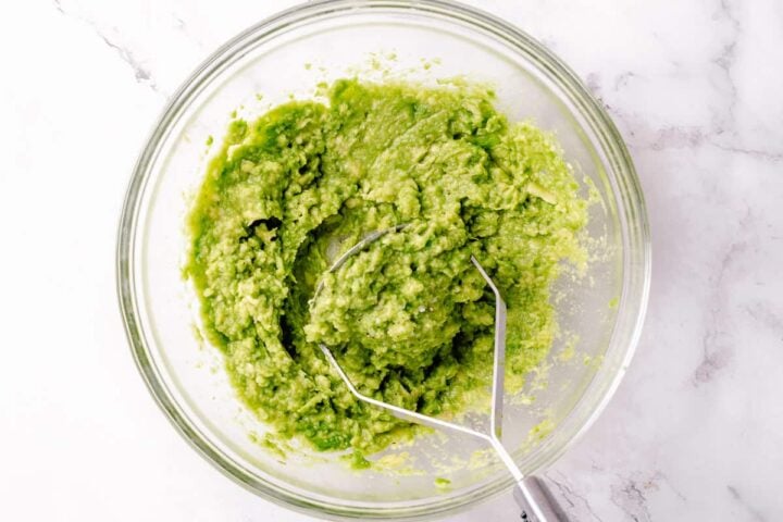 simple guacamole recipe process - mashed avocado in a glass bowl