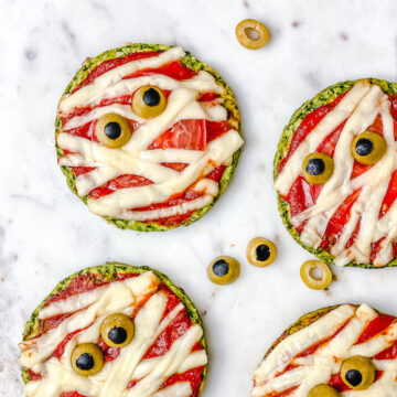 Halloween Mummy Pizzas - is the perfect Halloween party or dinner idea. Make these mummies with your kids for an easy and super flavorful Halloween themed meal. These mini pizzas are also gluten-free! The Yummy Bowl #savouryhalloweenfood #halloweenfoodrecipes #halloweenmummypizza #mummypizza #creepyhalloweenfoodideas #traditionalhalloweenfood #halloweentreats 