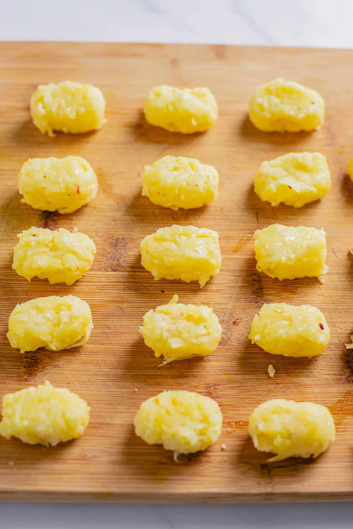 tater tots lined in rows on a baking dish before frying