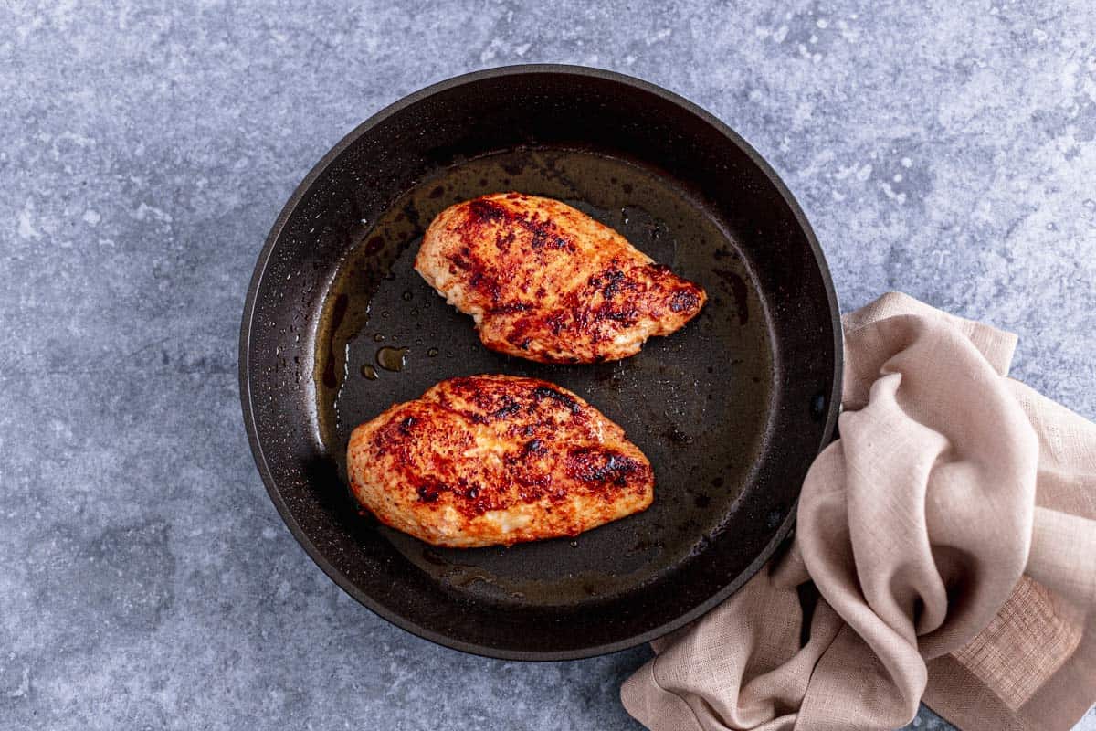 chicken breast rubbed with seasoning on a plate before cooking