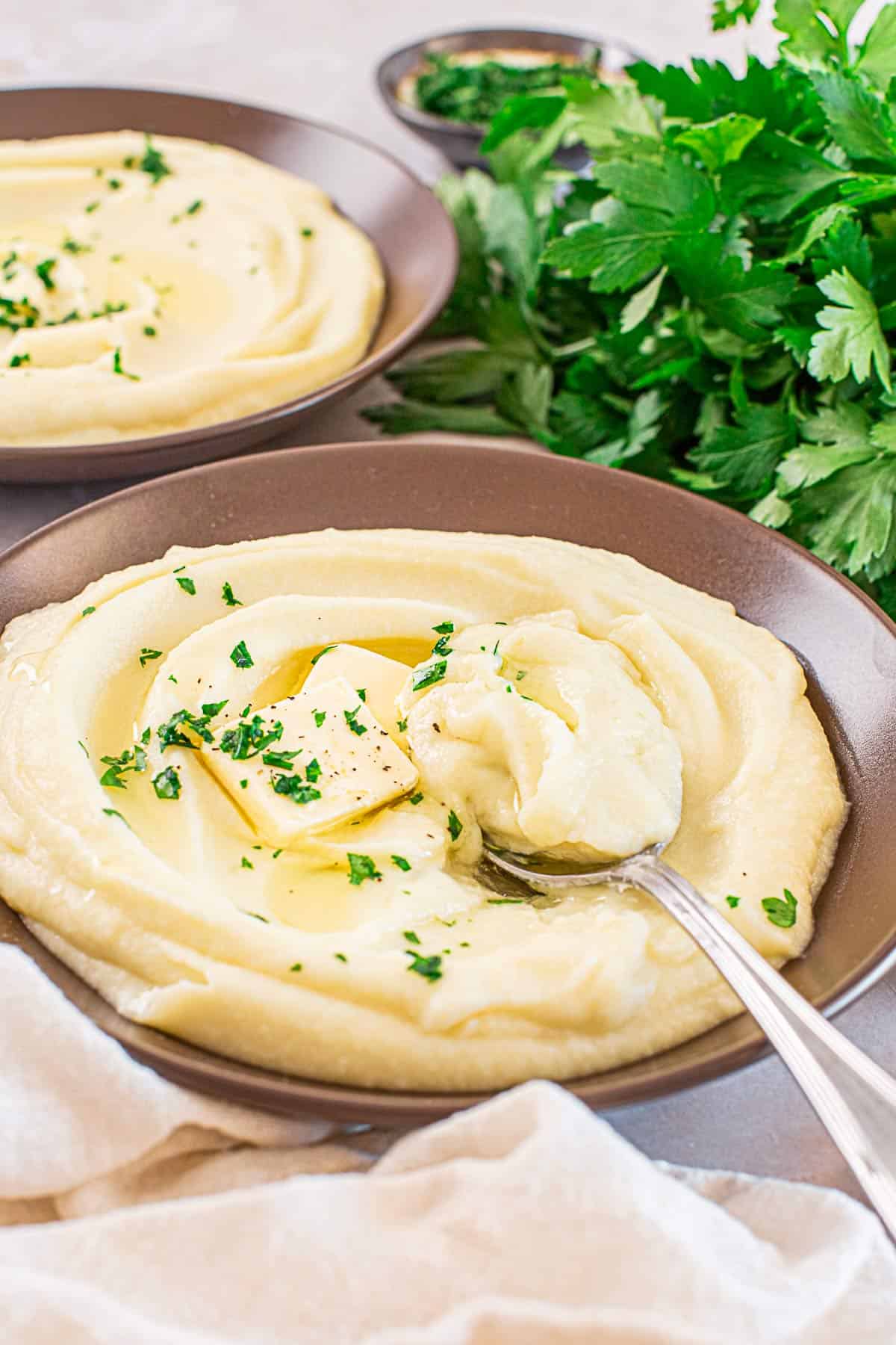 dark mashed potato and cauliflower bowl with a spoon inside