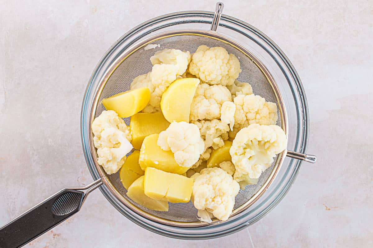 boiled cauliflower florets and diced potatoes in Colander