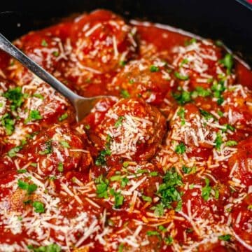 oven baked meatballs simmering in tomato sauce in a black skillet