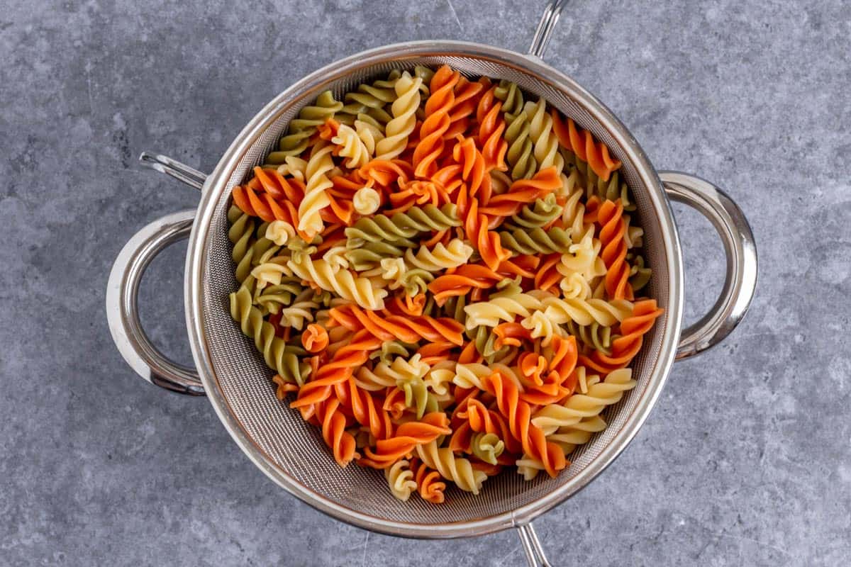 cooked tri color fusilli in a fine mesh strainer