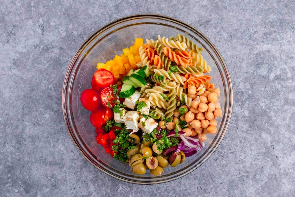 mediterranean pasta salad ingredients in a bowl with added dressing