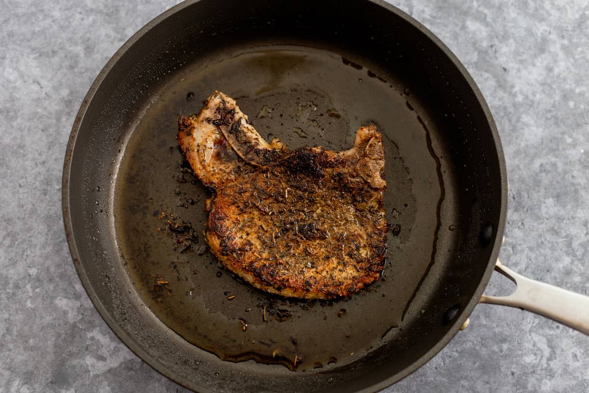 Pan Seared Pork Chops in a pan searing