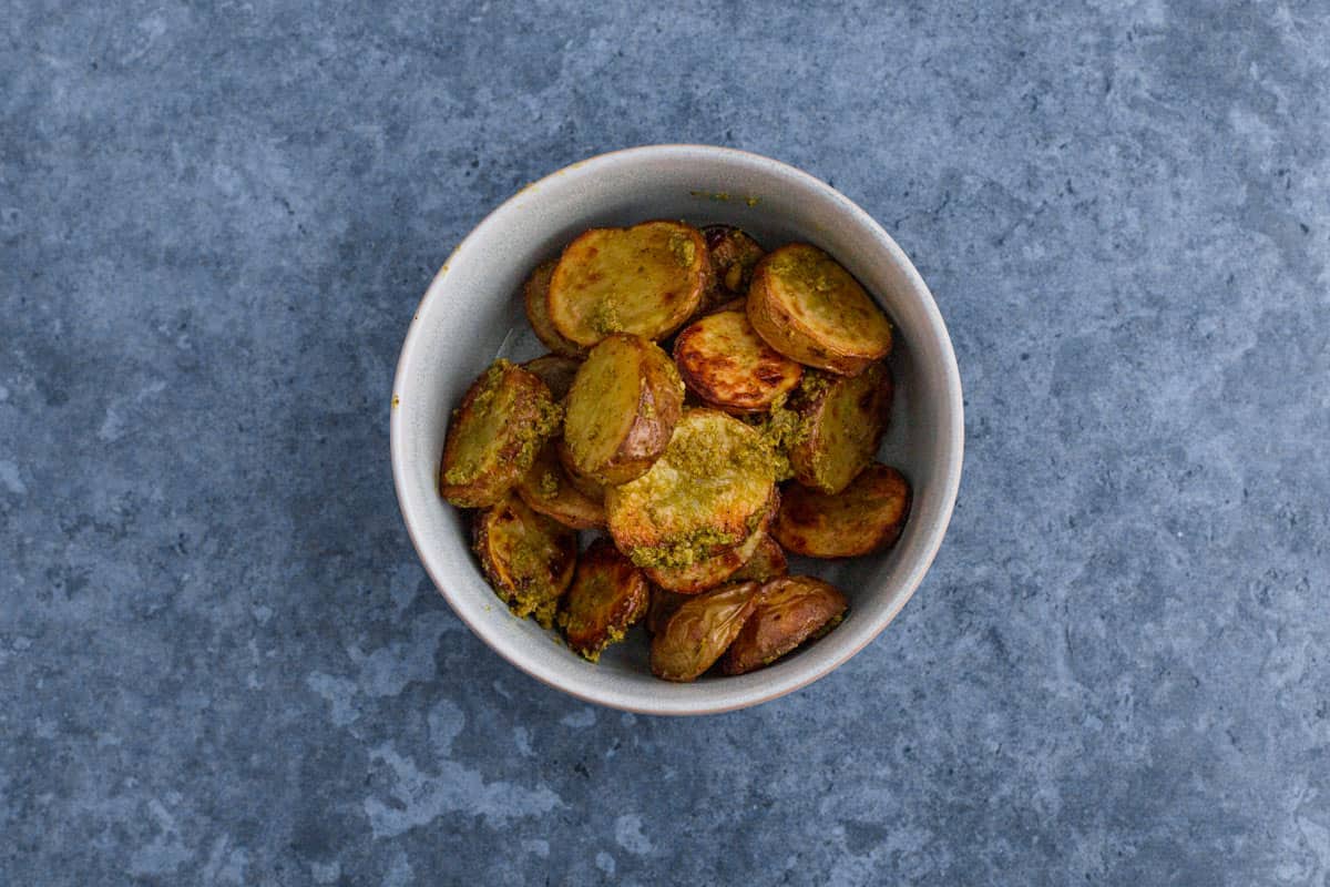 baked potatoes mixed with pesto in a bowl