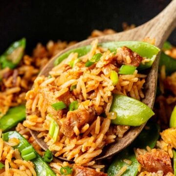 bbq pork fried rice in a wok skillet and a wooden spoon taking out the rice