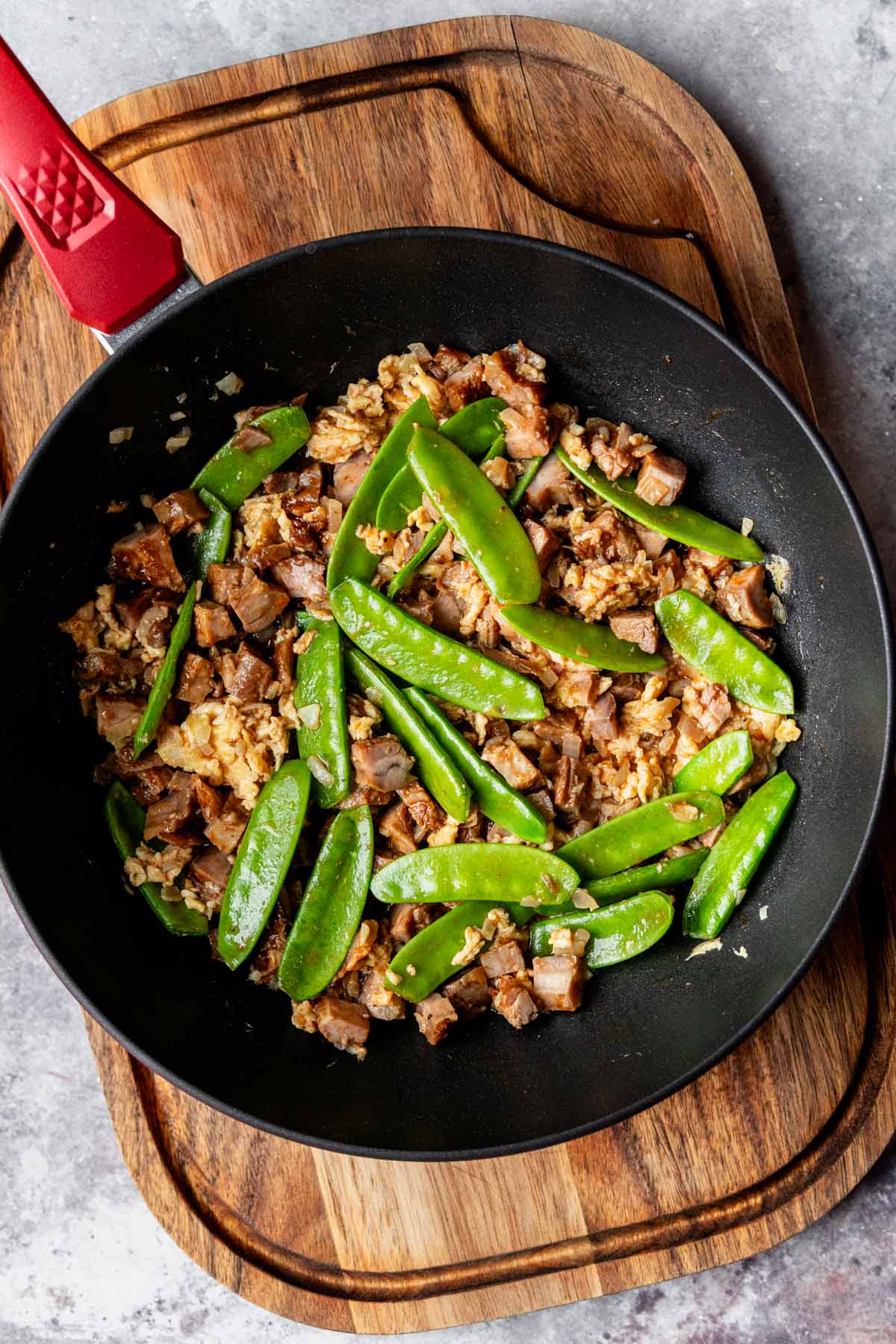 pork and snow peas fried in a wok skillet