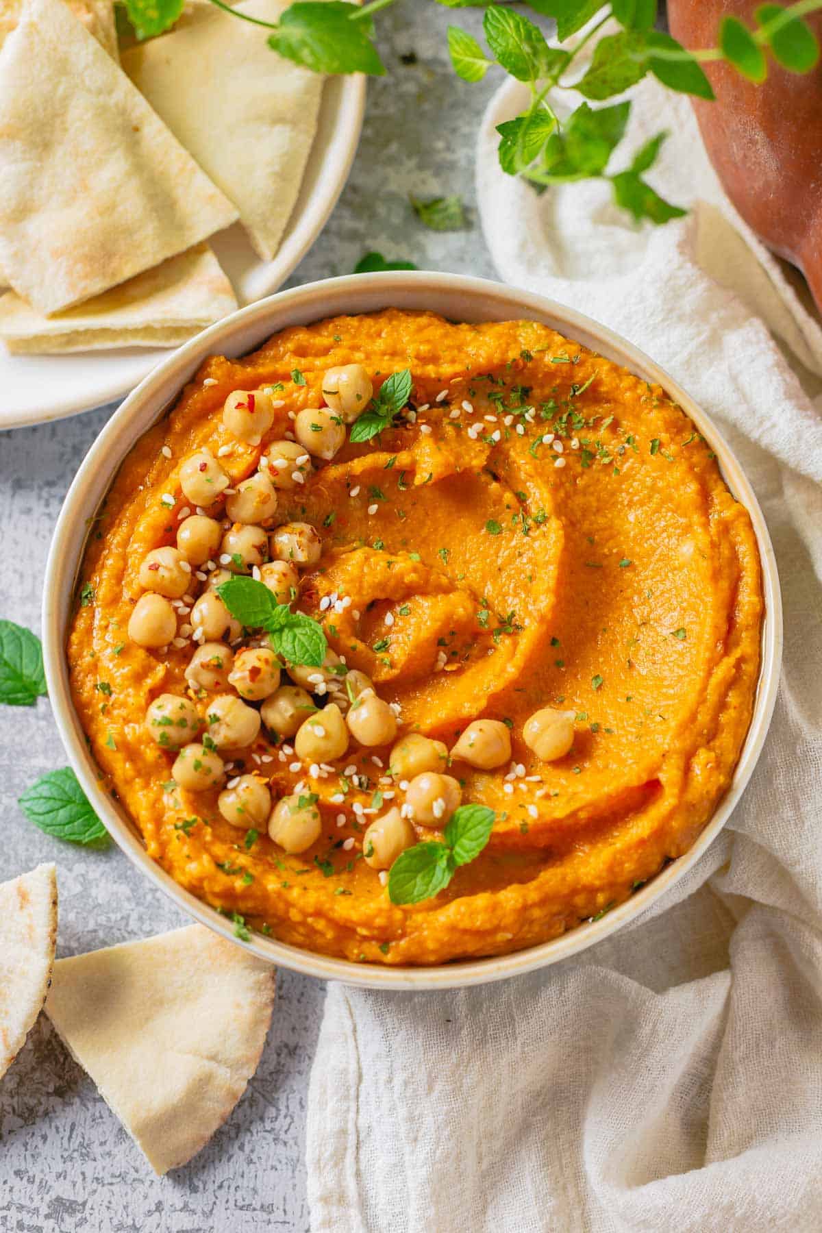 pumpkin and chickpea hummus in a white bowl on a marble table with white linen