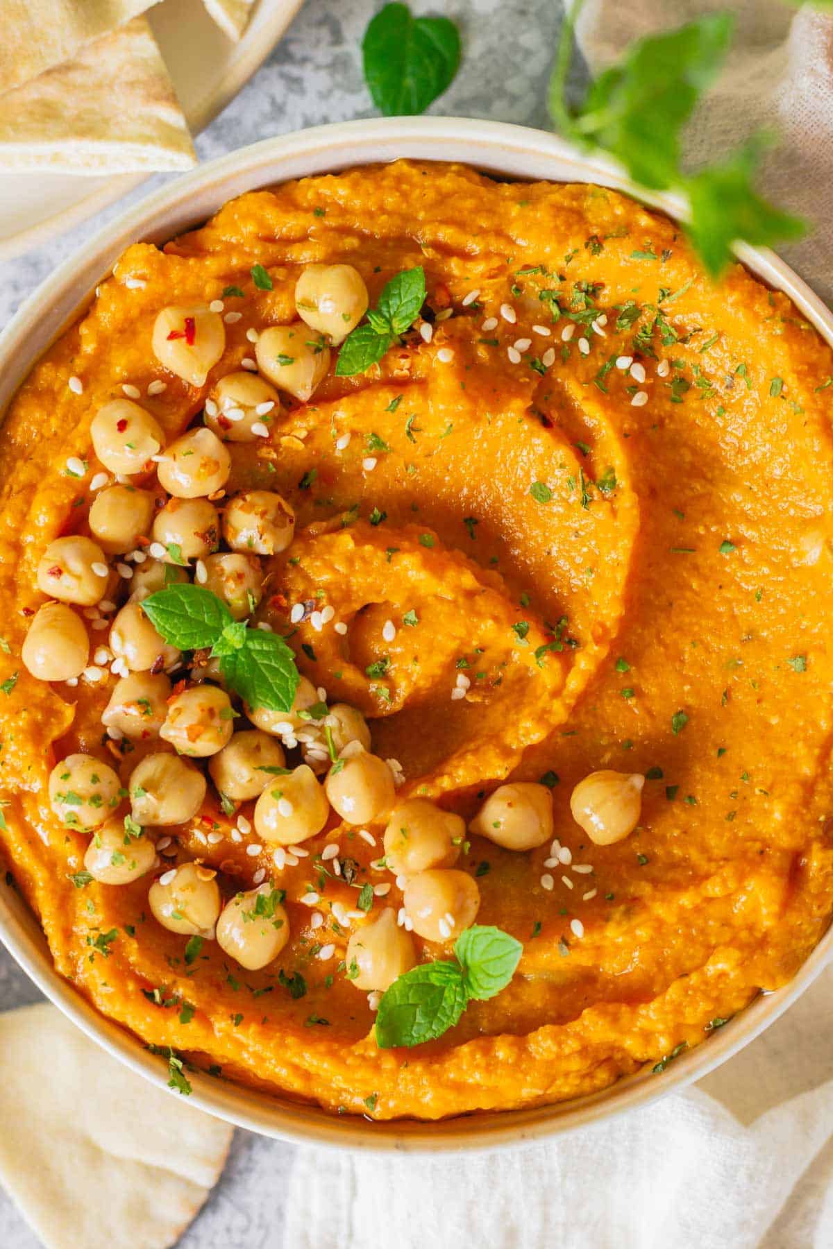 pumpkin and chickpea hummus in a white bowl on a marble table with white linen