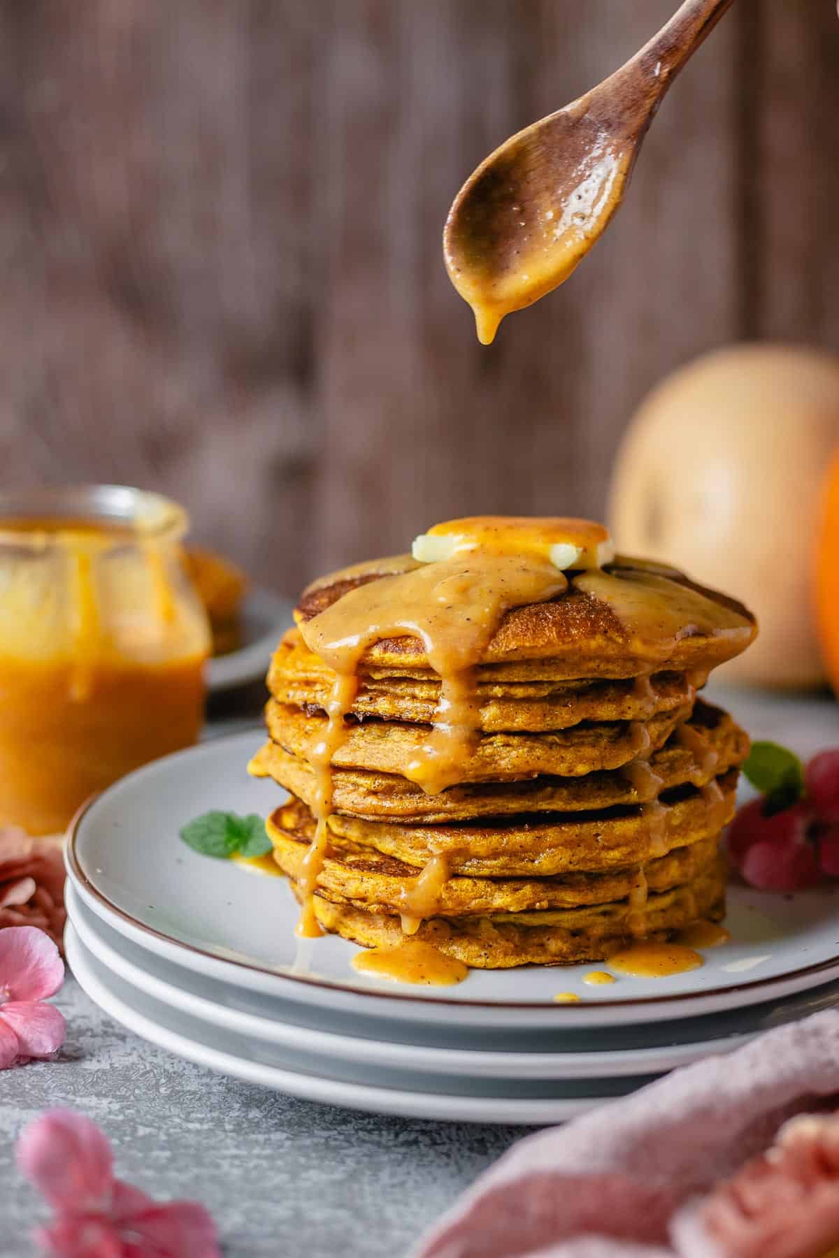 Stacked pumpkin pancakes side view angle with a drizzle of caramel