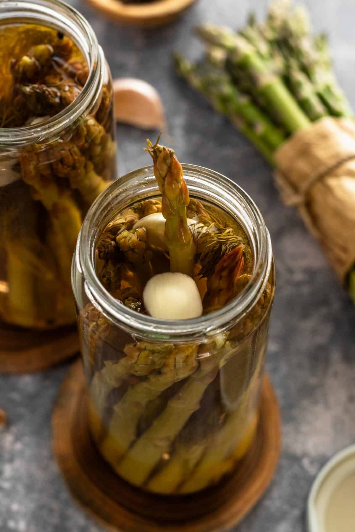 marinated asparagus spears in jars with garlic clove.