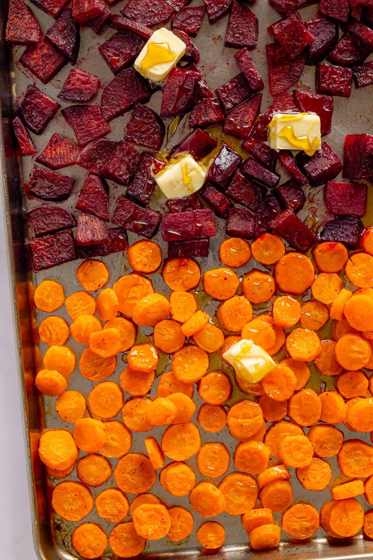 carrots and beets in baking sheet with butter cubes.