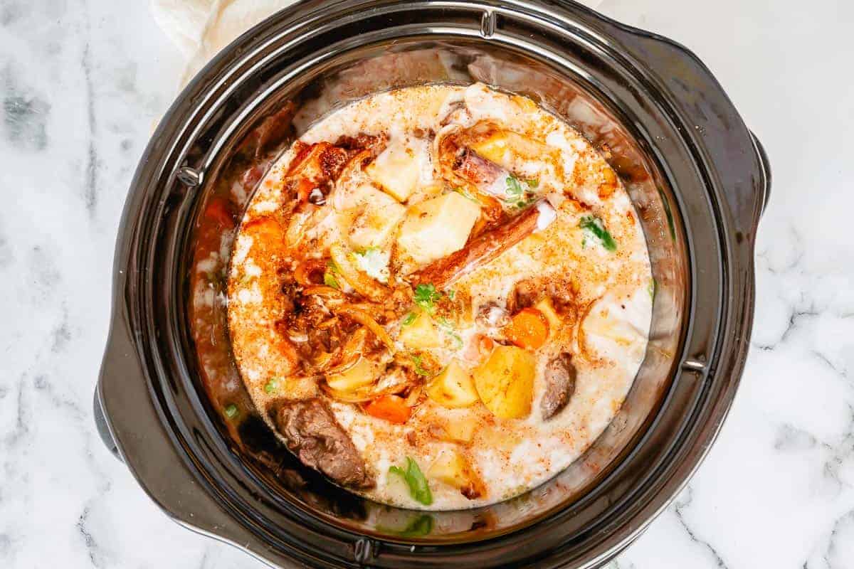 coconut milk added to the beef, vegetables, spices in a slow cooker pot